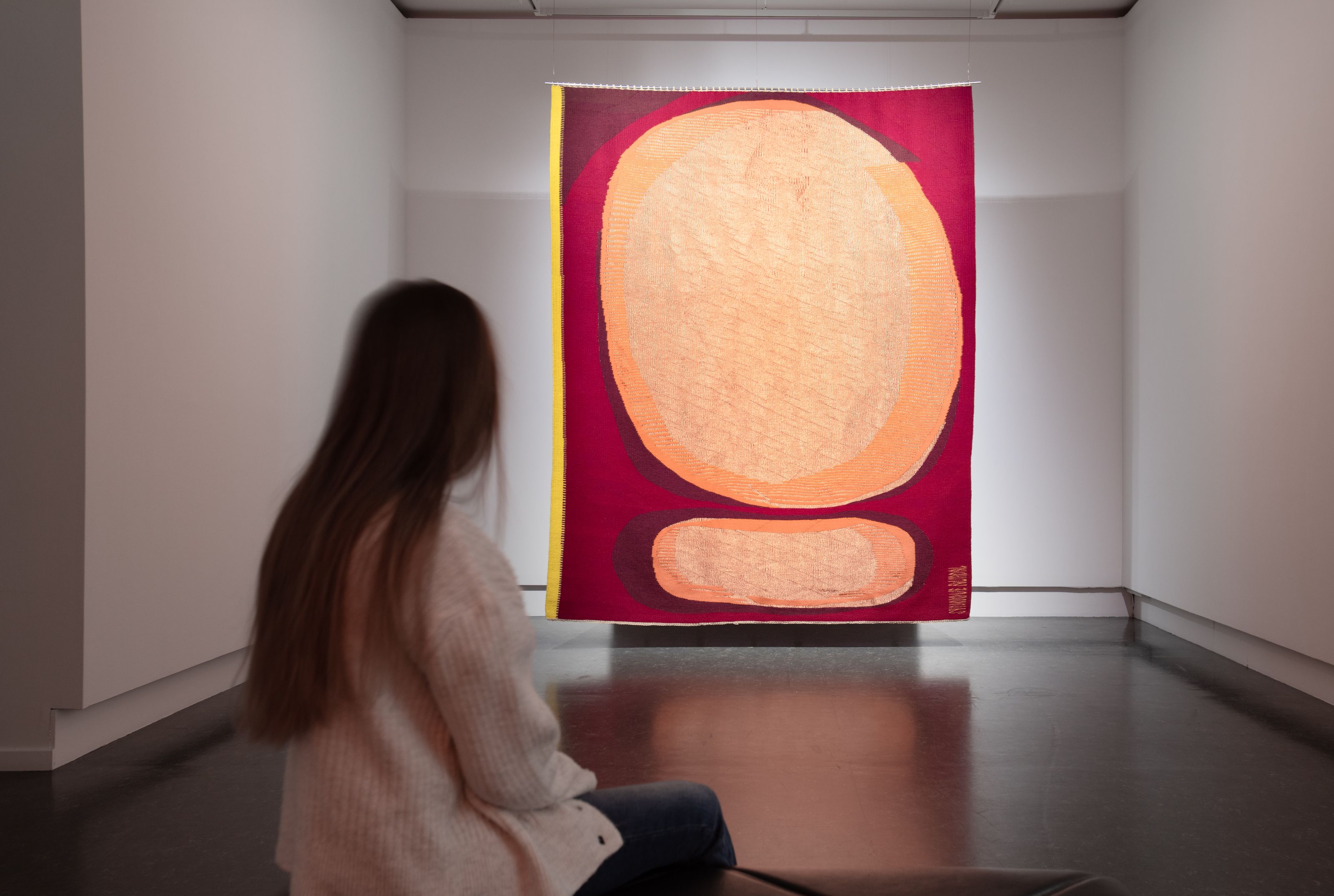 Kvinne med ryggen til ser på kunstverk fra Tangen-samlingen