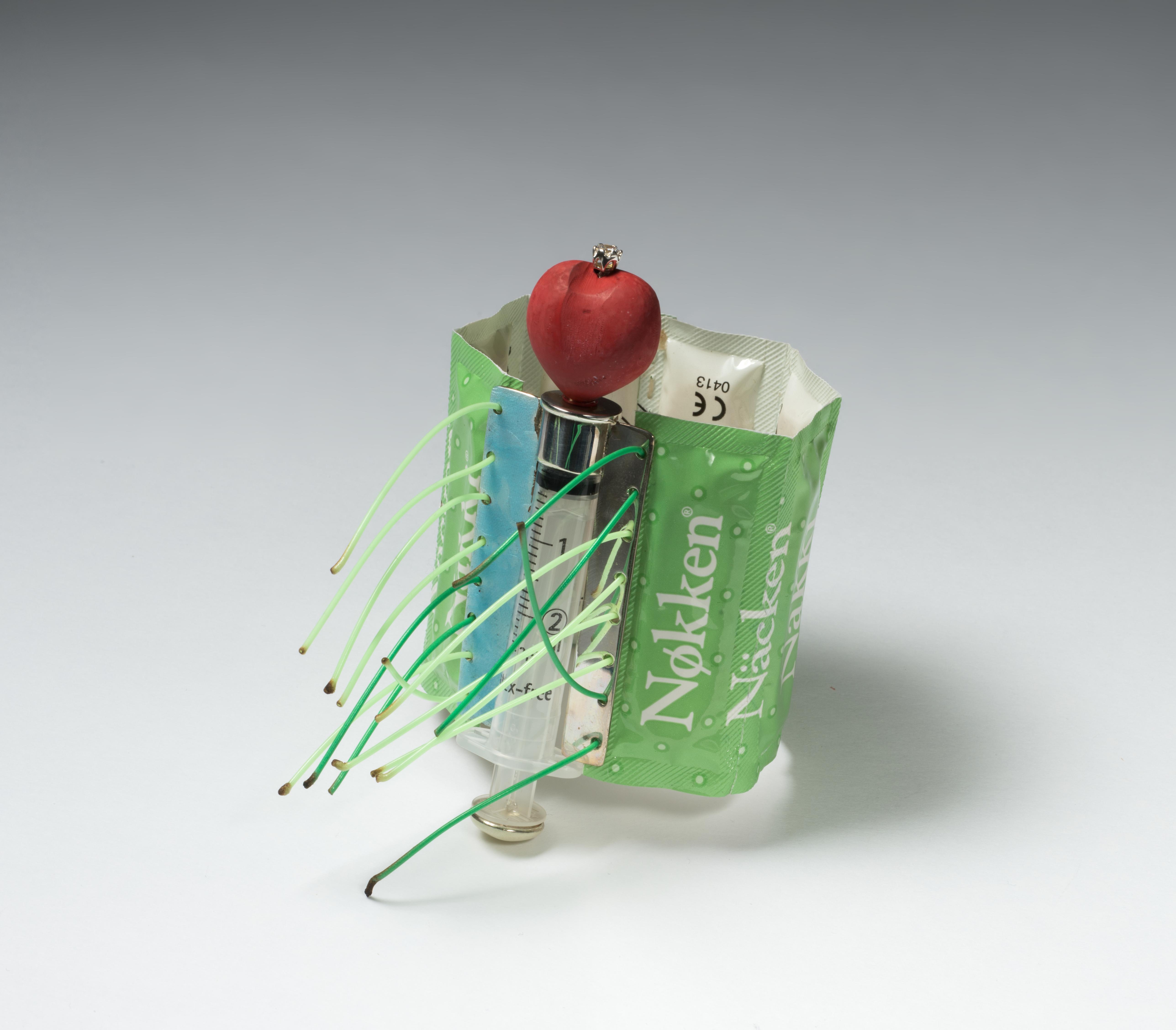 Kondompakninger og en sprøyte, kronet av et rødt hjerte