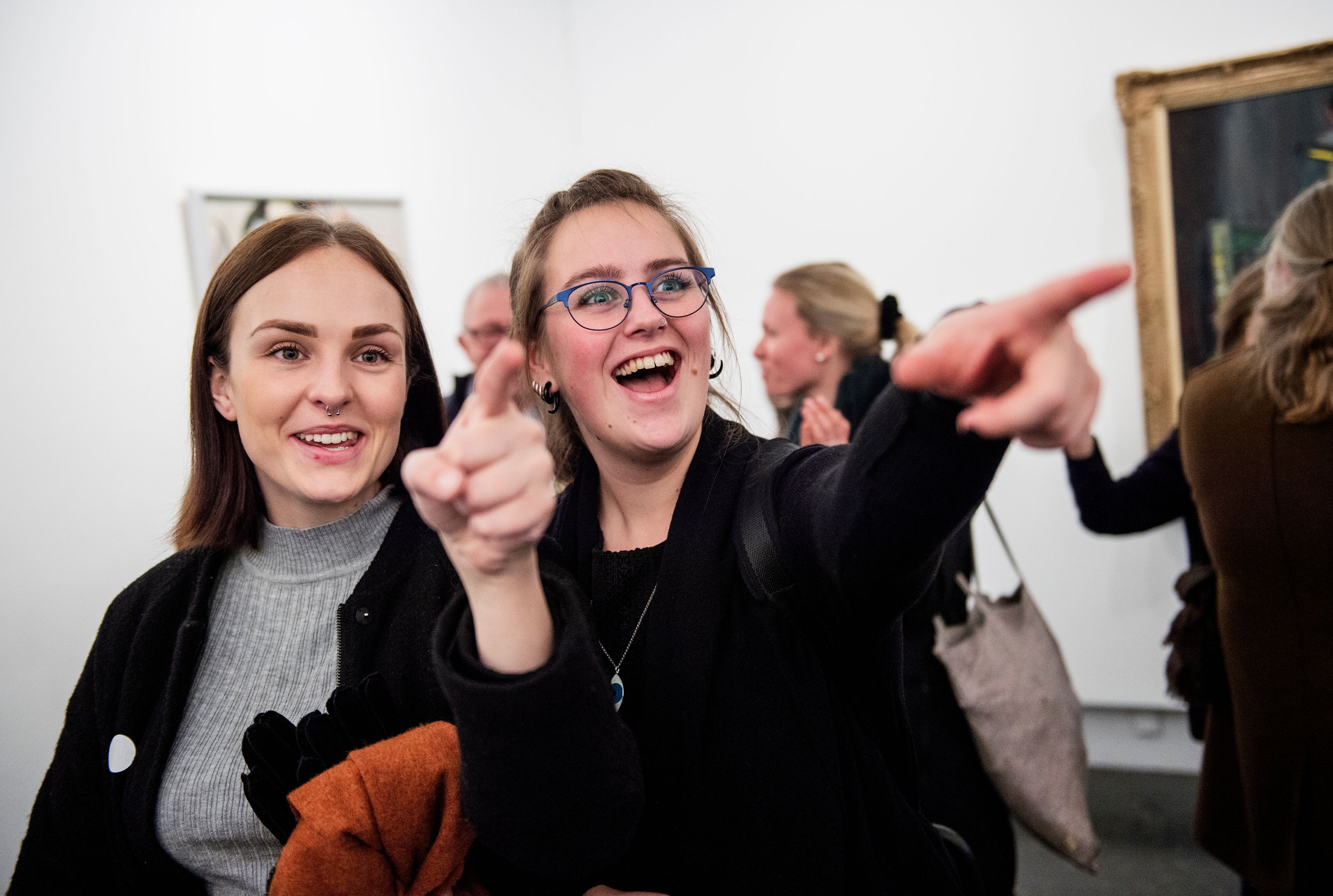 To personer står og ser på kunst i et mørkt galleri