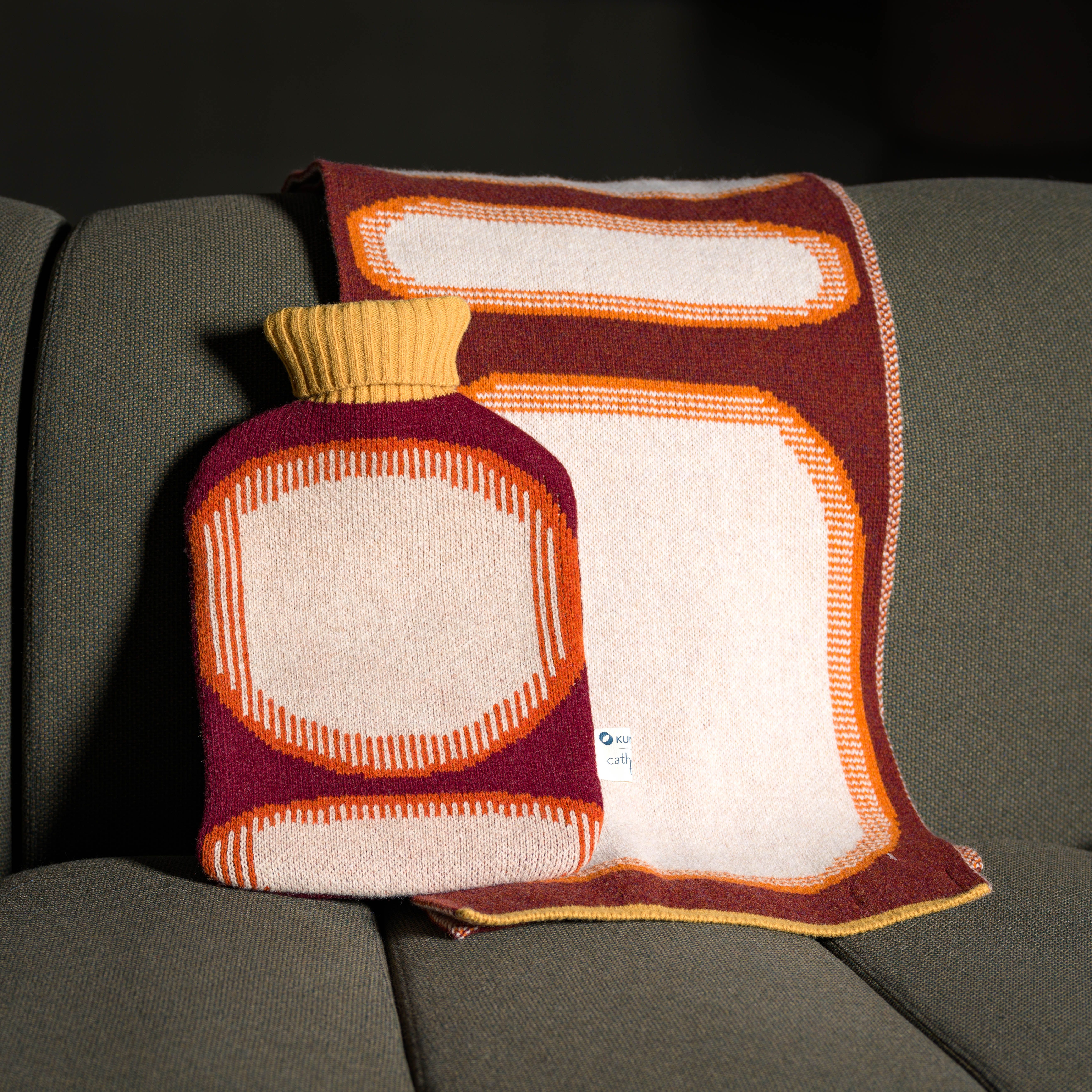 Varmeflaske og skjerf på en sofa 